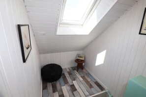 A small, narrow room with a sloped ceiling and a skylight, a black ottoman, a small wooden stool, and a radiator. - Pen Er Bed - GAVRES - Gîte (GAVRES)