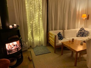 Ein gemütliches Wohnzimmer mit Kamin, einer Couch, einem Couchtisch und einer Lampe.