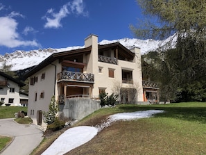 A multi-story building with balconies, a wooden fence, and a snow-covered path. - Auf den Böden Haus B Appartement/Fewo,   Auf den Böden Haus B by Interhome (Parpan)