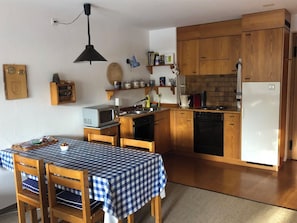 Cocina compacta con muebles de madera, microondas, lavaplatos y refrigerador.