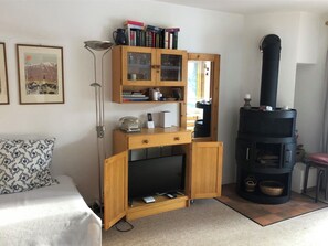 Ein gemütliches Wohnzimmer mit einem Holz-Fernseherstand, einem Kamin und einem Bücherregal.