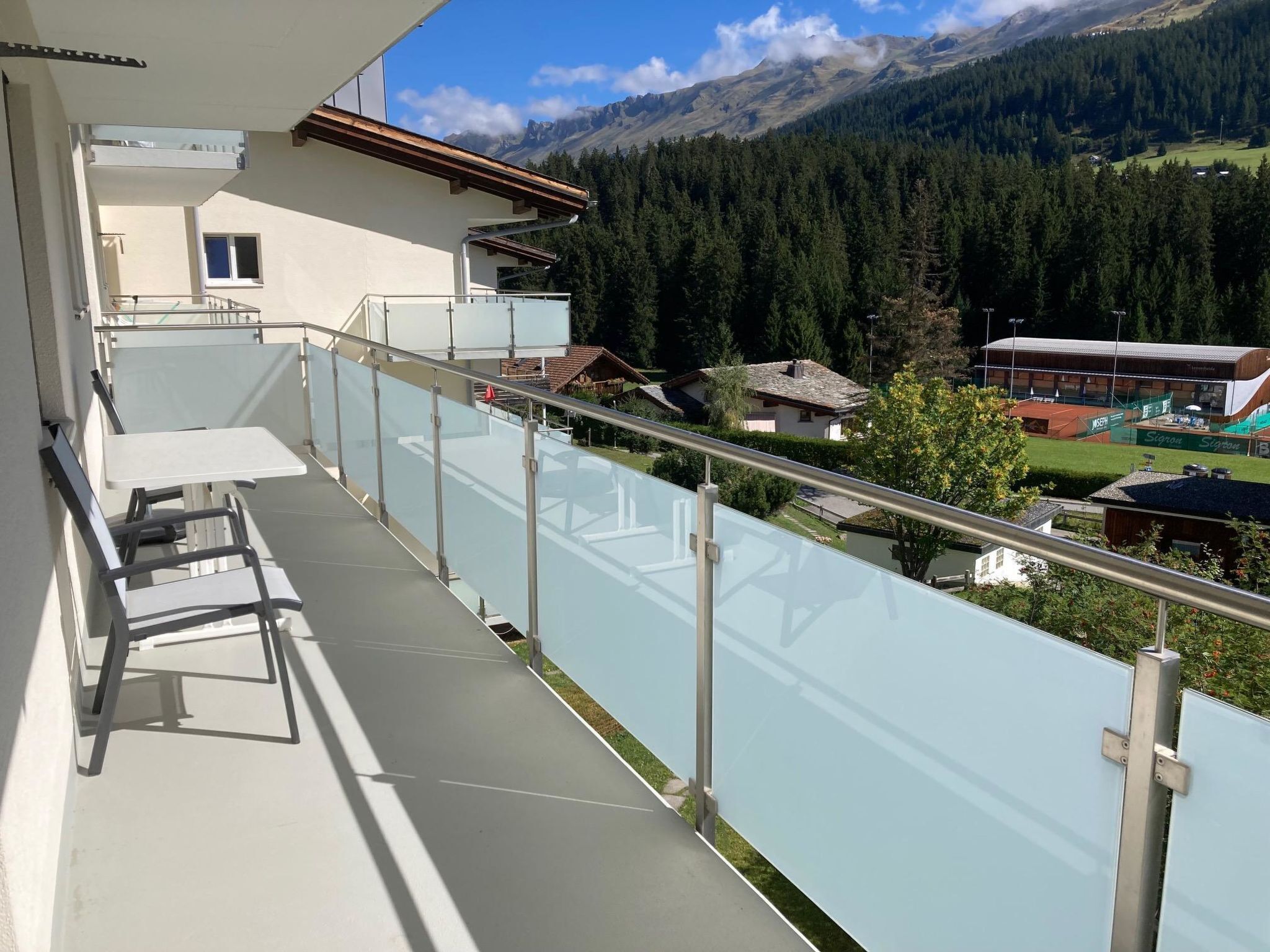 A balcony with a glass railing overlooking a mountainous landscape.