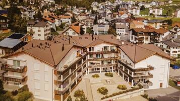 Ein mehrstöckiges Hotel mit Balkonen, einem Parkplatz und einem roten Auto davor.