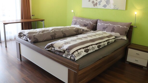 Een slaapkamer met een houten bed, twee nachtkastjes en een groene wand.