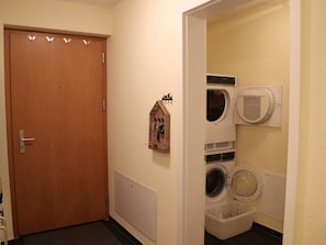 Ein Waschraum mit Holztür, an der Wand befestigtem Wäscheständer und gestapelten Wäschekörben.