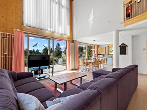 Ein geräumiges Wohnzimmer mit großem Flachbildfernseher, einer Couch und einem Essbereich mit Tisch und Stühlen.