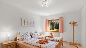 A bedroom with a bed, bedside tables, a lamp, a window with curtains, and a painting on the wall. - Golden Peaks Ferienhaus Ferienhaus, Dusche und Bad, WC, 4 oder mehr Schlafräume by Interhome (Valbella)