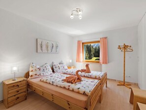 Ein Schlafzimmer mit Bett, Nachttischen, einer Lampe, einem Fenster mit Vorhängen und einem Bild an der Wand.