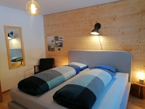 A bedroom with a bed, a chair, a mirror, and a wooden wall. - CANOLS#32 Appartement/Fewo 4-Bettwohnung (2-Zimmerwohnung) by Interhome (Valbella)