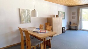 Een eethoek met een houten tafel en stoelen, een hanglamp en een kast met kunstwerken.
