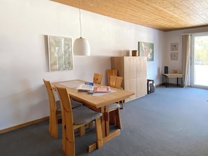 A dining area with a wooden table and chairs, a hanging light fixture, and a cabinet with artwork. - Haus Montana 2/9 Appartement/Fewo,   4-Bettwohnung by Interhome (Lenzerheide)
