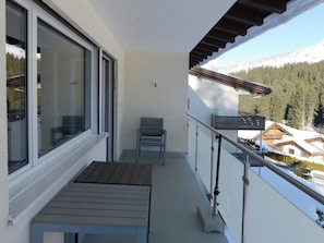 A balcony with a table and chairs, overlooking a snowy landscape with houses and trees. - Haus Montana 2/9 Appartement/Fewo,   4-Bettwohnung by Interhome (Lenzerheide)