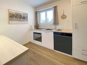 A compact kitchen with a dishwasher, oven, and a window above the sink. - Haus Montana 2/9 Appartement/Fewo,   4-Bettwohnung by Interhome (Lenzerheide)
