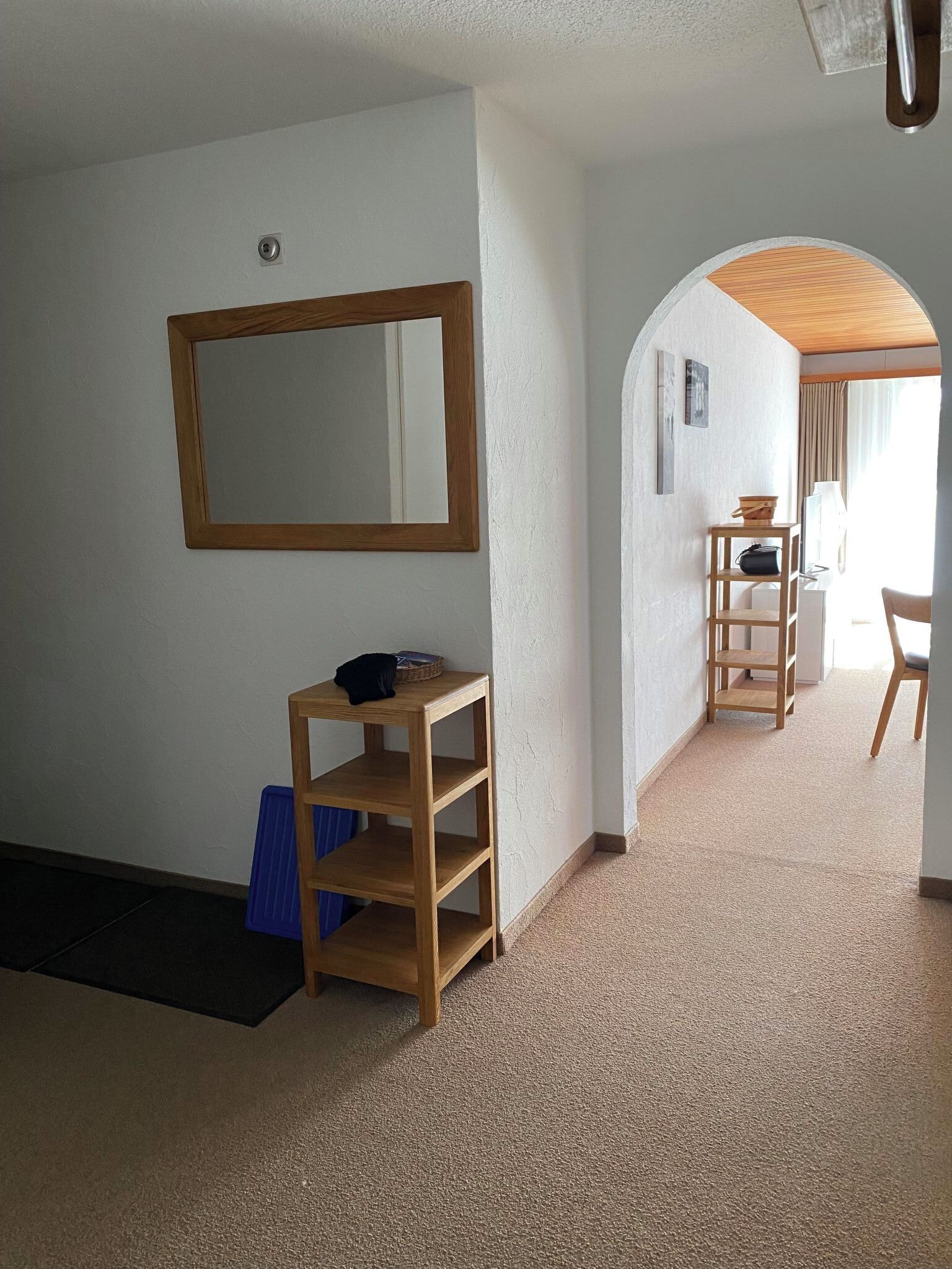 A room with a wooden floor, a mirror on the wall, a small wooden table, and a chair.