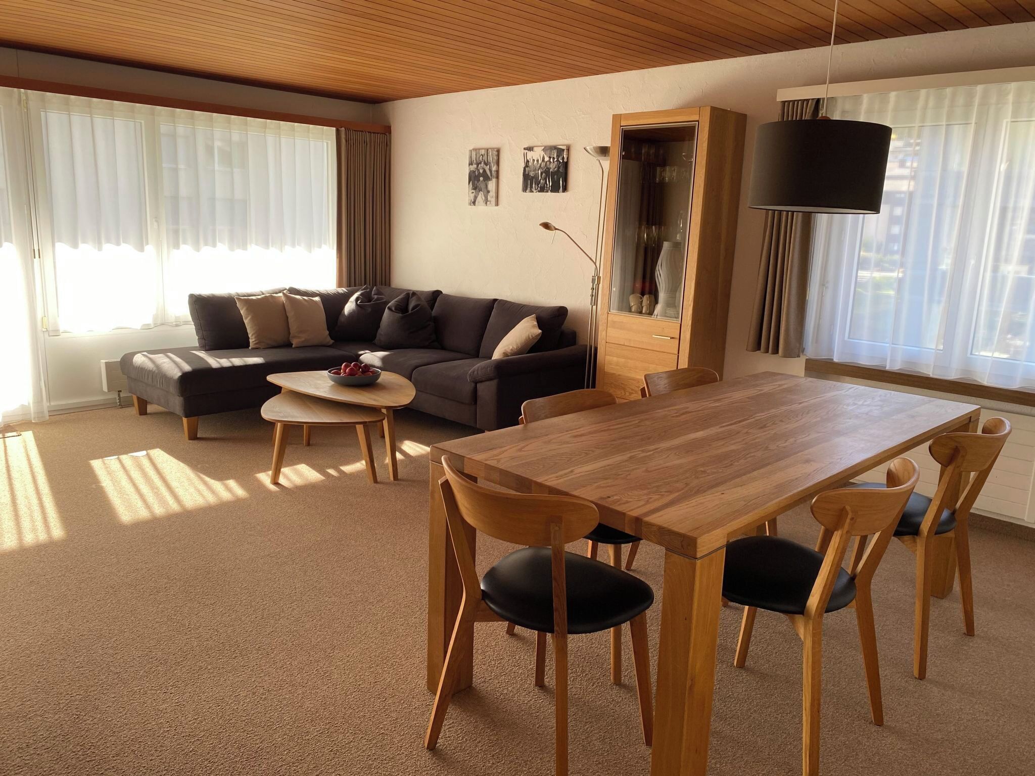 Ett vardagsrum med en soffa, ett soffbord, ett matbord, stolar och en tv.