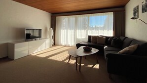 Ein Wohnzimmer mit Fernseher, Sofa und Couchtisch.