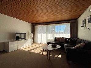 Ein Wohnzimmer mit Fernseher, Sofa und Couchtisch.