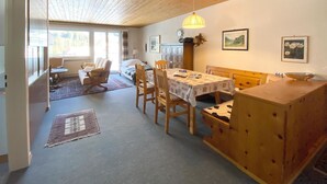 A cozy room with a wooden ceiling, a dining table with chairs, a sofa, and a window with a view of trees. - Haus Montana 2/4 Appartement/Fewo,   4-Bettwohnung by Interhome (Lenzerheide)