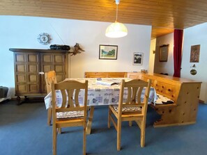 Un coin repas avec une table en bois, des chaises et un banc. On y trouve également un meuble en bois et un luminaire suspendu.