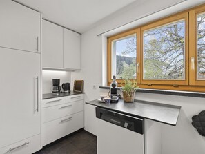 A modern kitchen with white cabinets, a black countertop, and a window with a view of trees. - Bellavista 6 Appartement/Fewo, Bad, WC, 3 Schlafräume Ferienwohnung Bellavista 6 by Interhome (Parpan)