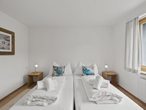 A double room with two beds, nightstands, and a framed picture on the wall. - Bellavista 6 Appartement/Fewo, Bad, WC, 3 Schlafräume Ferienwohnung Bellavista 6 by Interhome (Parpan)