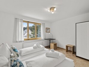Un dormitorio moderno con un ventanal grande, una cama, un escritorio y un armario.