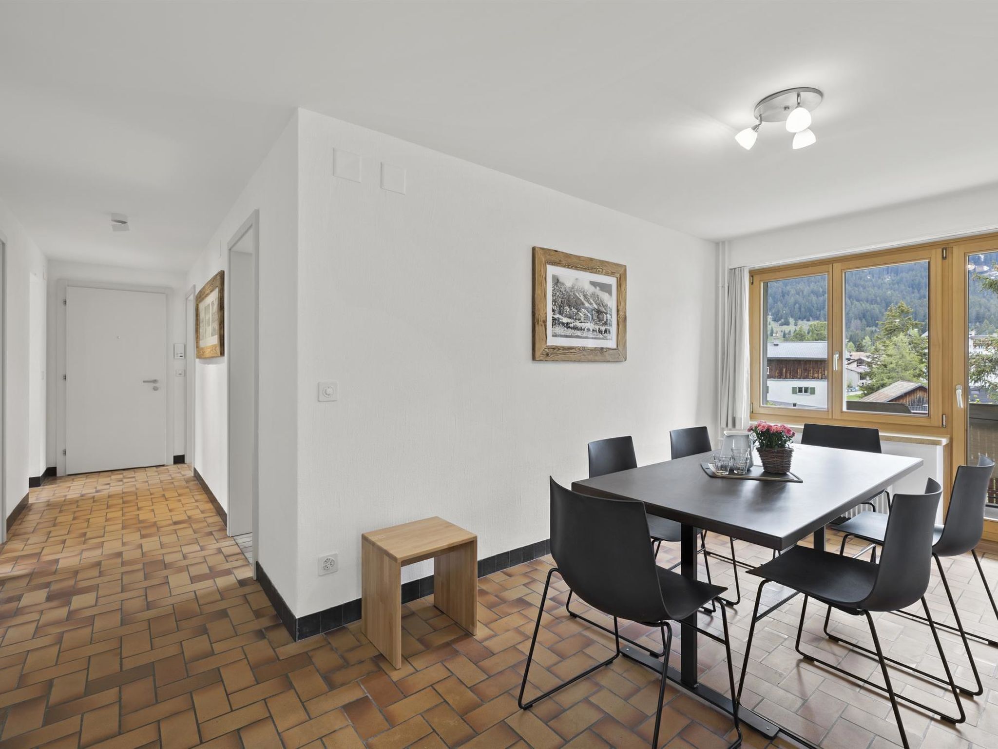 A dining area with a table and chairs, a wooden bench, and a framed picture on the wall.