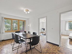 A modern dining area with a dark wooden table and black chairs, large windows with curtains, and a view of the outdoors. - Bellavista 6 Appartement/Fewo, Bad, WC, 3 Schlafräume Ferienwohnung Bellavista 6 by Interhome (Parpan)
