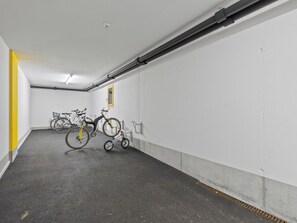 A parking garage with bicycles parked against the walls.