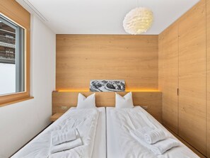 Ein modernes Schlafzimmer mit einem hölzernen Kopfende, einem Bett mit weißen Leinen und einem dekorativen Wandbild.