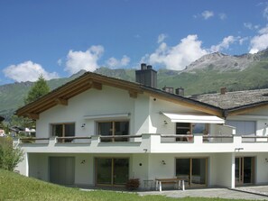 A two-story house with a balcony, large windows, and a mountain backdrop. - Praval Appartement/Fewo Ferienwohnung Praval by Interhome (Valbella)