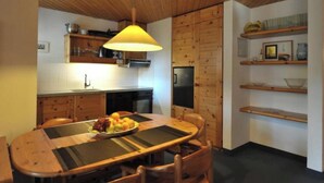 Una cucina compatta con mobili in legno, un forno integrato e un tavolo da pranzo con un sottopiattino.