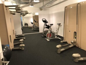 A gym with exercise equipment, a mirrored wall, and a door. - Studers Lenzerheide Appartement/Fewo Schweizerhof Nr. 311 by Interhome (Lenzerheide)