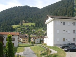 A residential area with a paved path, houses with sloped roofs, and a mountain backdrop. - Moser Appartement/Fewo Ferienwohnung Moser by Interhome (Churwalden)