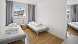 Et moderne hotelværelse med to senge, et sengebord, en lampe og et stort spejl.