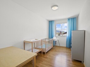 A room with a crib, a high chair, a table, and a refrigerator. - Moser Appartement/Fewo Ferienwohnung Moser by Interhome (Churwalden)