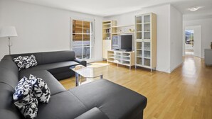 En moderne stue med en grå sofa, et glasbord og et tv-møbel med et fladskærms-tv.