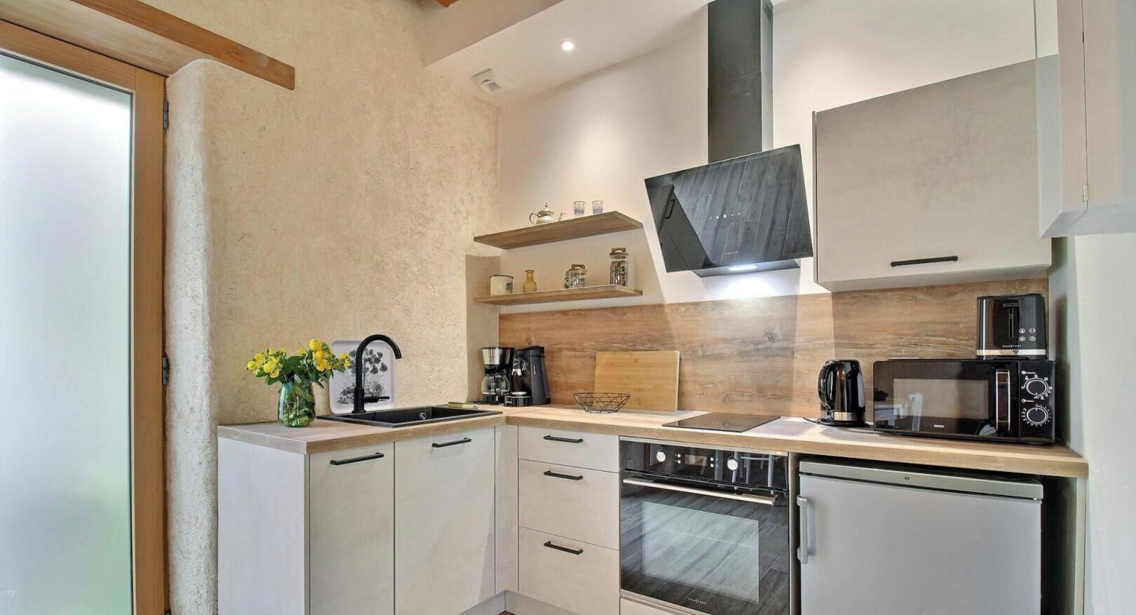 A modern kitchen with white cabinets, a built-in oven, a microwave, and a coffee maker.