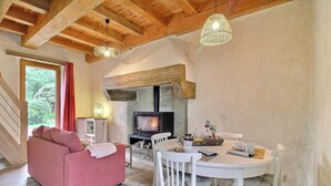 A cozy living room with a fireplace, a sofa, a dining table with chairs, and a TV. - The swallow's nest - LANGONNET (LANGONNET)