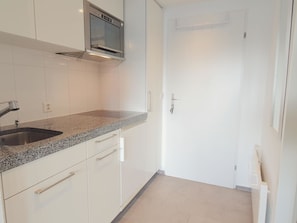 A modern kitchen with a stainless steel sink, granite countertop, and white cabinetry. - Studio 406 Appartement/Fewo Studio 406 by Interhome (Lenzerheide)