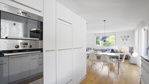 A modern kitchen with stainless steel appliances, white cabinetry, and a dining area with a wooden floor. - Liebrand Appartement/Fewo Ferienwohnung Liebrand by Interhome (Churwalden)