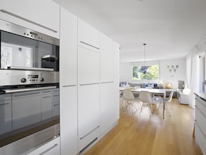 A modern kitchen with stainless steel appliances, white cabinetry, and a dining area with a wooden floor. - Liebrand Appartement/Fewo Ferienwohnung Liebrand by Interhome (Churwalden)