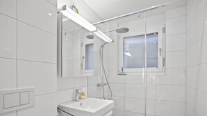 A modern bathroom with a glass-enclosed shower, a white sink, and a mirror above the vanity. - Liebrand Appartement/Fewo Ferienwohnung Liebrand by Interhome (Churwalden)