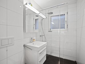 A modern bathroom with a glass-enclosed shower, a white sink, and a mirror above the vanity. - Liebrand Appartement/Fewo Ferienwohnung Liebrand by Interhome (Churwalden)