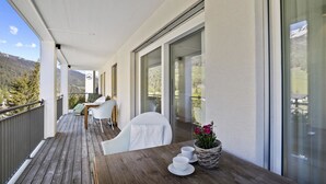 A wooden deck with a table and chairs, overlooking a mountainous landscape. - Liebrand Appartement/Fewo Ferienwohnung Liebrand by Interhome (Churwalden)