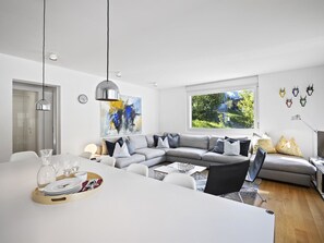 A modern living room with a dining area, a large window, and a view of greenery outside. - Liebrand Appartement/Fewo Ferienwohnung Liebrand by Interhome (Churwalden)