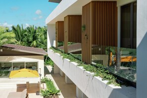 A modern building with a balcony, a yellow umbrella, and a view of palm trees. - Shemesh Residence - Ocean & golf views with full staff at unique Cap Cana villa (Cap Cana)