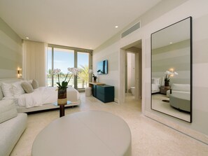 A modern hotel room with a large bed, a round coffee table, a TV, and a large mirror. - Shemesh Residence - Ocean & golf views with full staff at unique Cap Cana villa (Cap Cana)