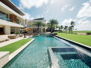 Ein moderner Poolbereich mit klarem Pool, Liegestühlen und einem gepflegten Rasen.