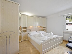 A bedroom with a bed, wooden wardrobe, and a window with a view of a building outside. - Ruggli Appartement/Fewo,   Ferienwohnung Ruggli by Interhome (Churwalden)